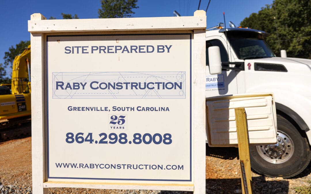 A construction site sign with phone number for Raby Construction.